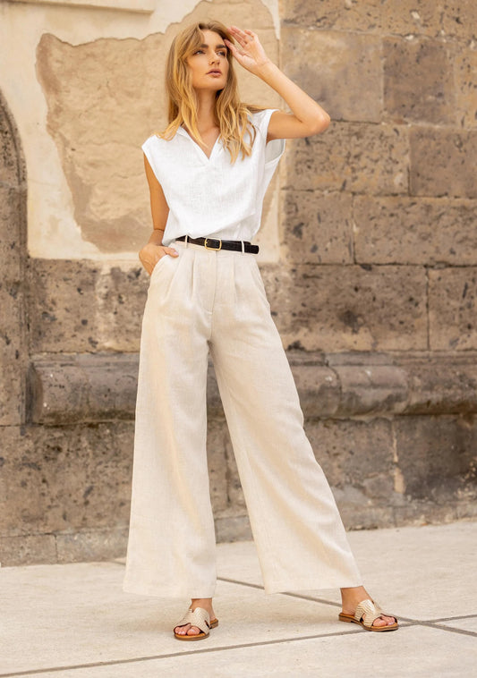 Pantalon femme beige à coupe large et taille haute porté avec un top blanc